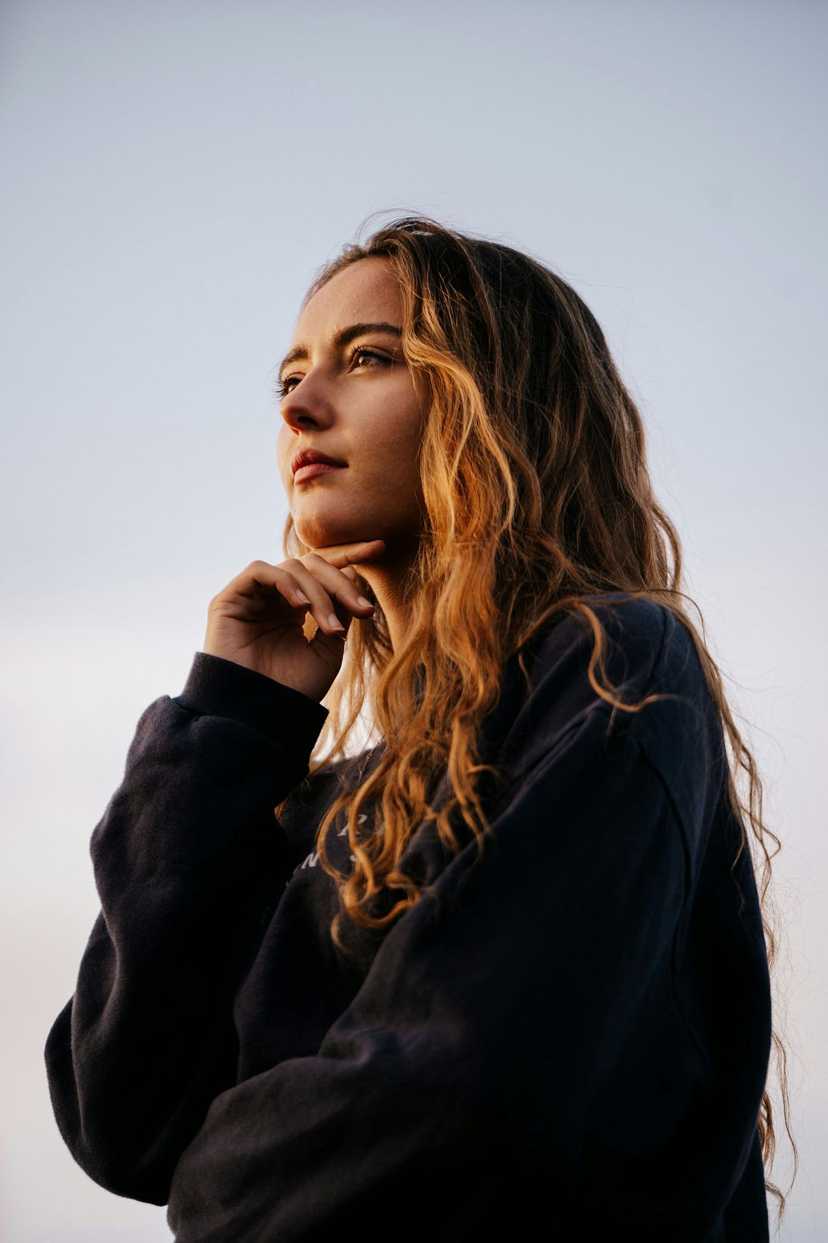 High school senior posing confidently outdoors in natural light.
