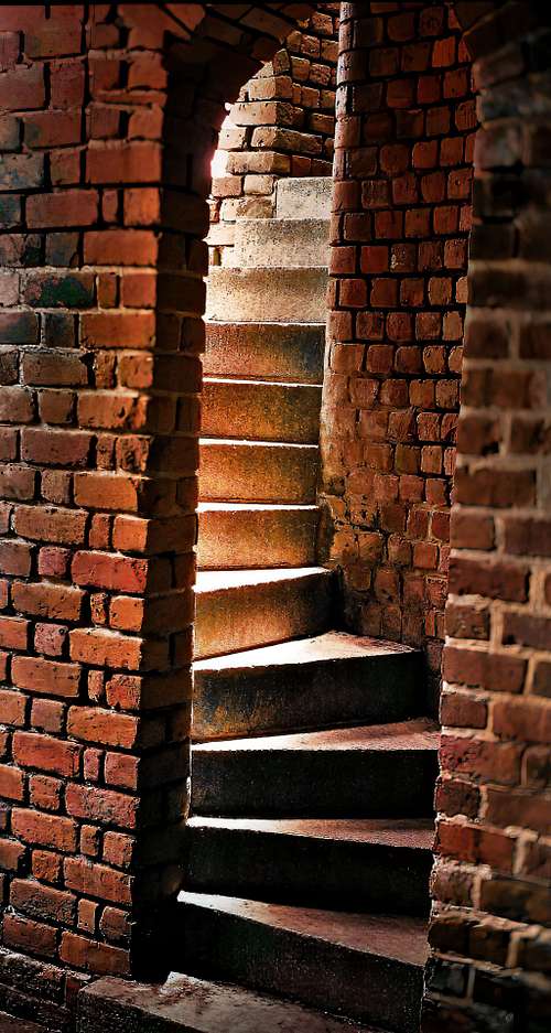 Elegant curved staircase amidst red brick walls.