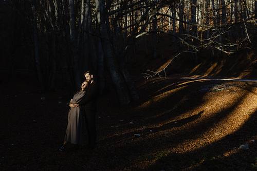 Donna che cammina da sola su un sentiero nel bosco marchigiano con striscia di luce dorata.