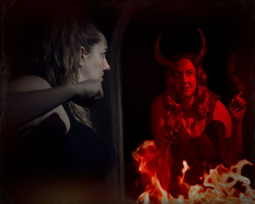 A woman aims her fist at the red devil version of herself looking back at her in the mirror.