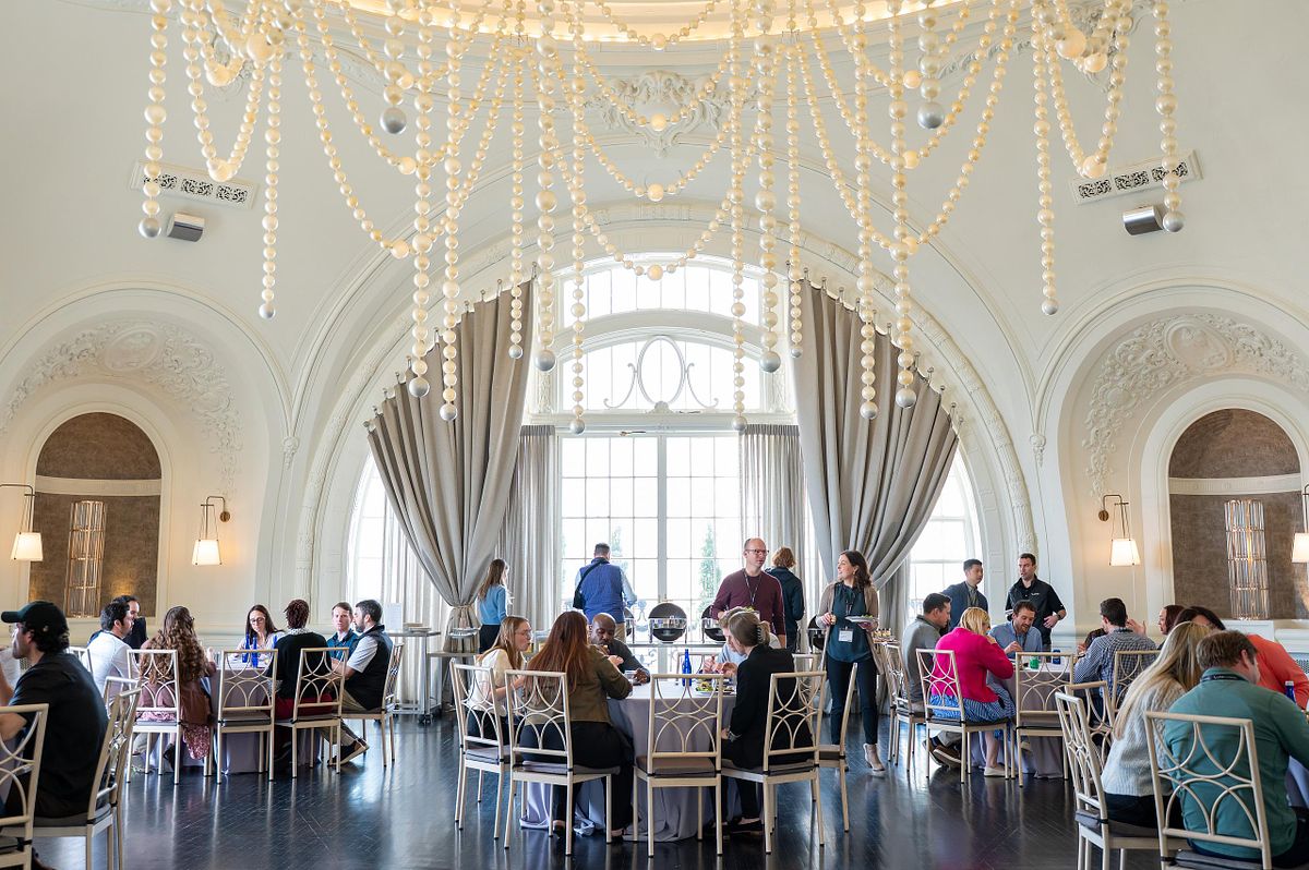Wide view of a corporate event in the Pearl Room at the Bellevue Hotel in Philadelphia with attendees seated beneath chandelier decor