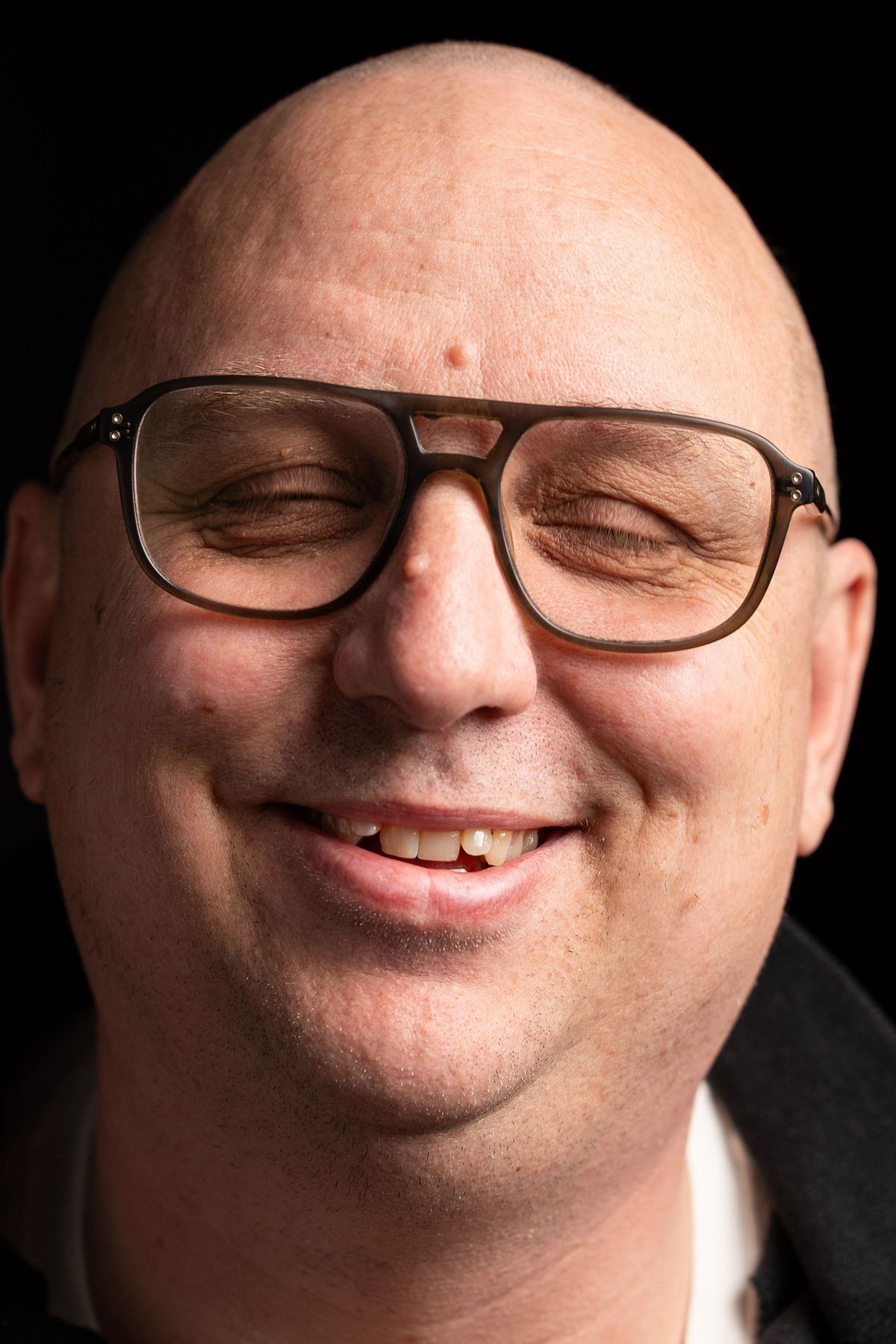 Leende man med glas&ouml;gon i mjukt studioljus, autentiskt uttryck