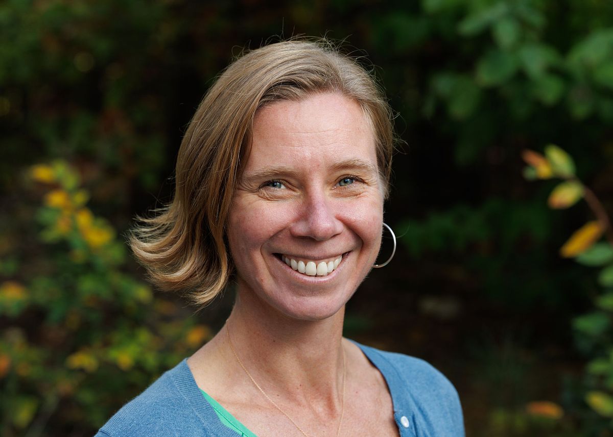A close-up headshot of a woman against a wooded backdrop at UNC's Chapel Hill campus