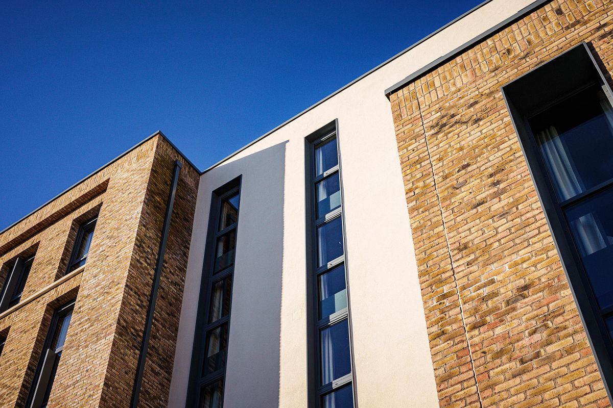 Close-up detail of the Easy Hotel Dublin's facade, showing the contrast between the light-colored rendered sections and the textured brickwork. Rectangular windows with dark frames are visible.