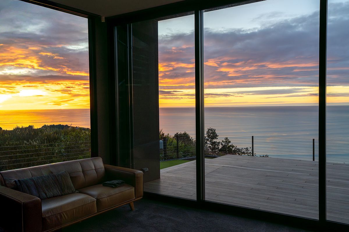 Luxury interior architectural photography of a modern living room with sunset ocean views in Raglan by Flax Cove Studio.