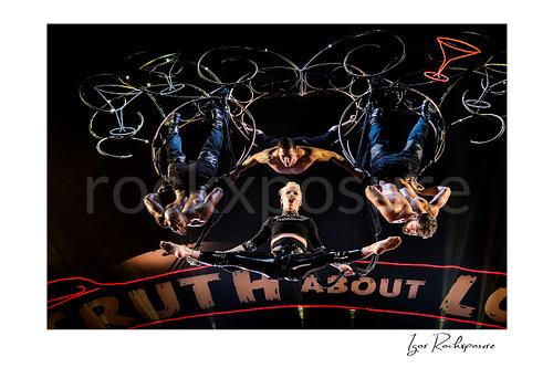 Horizontal color image of Pink performing onstage with aerial acrobats and glowing martini glass props above her