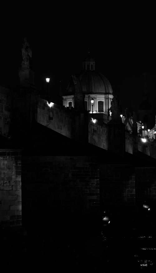 Les statues se découpent dans l’obscurité, guidant le regard vers le dôme éclairé. Une vision intime du pont Charles, entre silence et architecture.