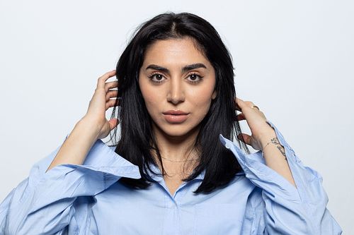 Studioporträtt av skådespelare i ljusblå skjorta med tydlig blick, neutral bakgrund och skarpt, rent uttryck.