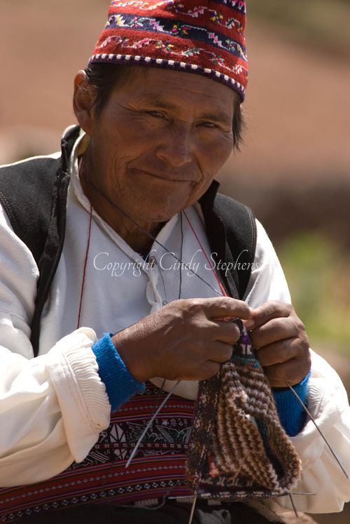 Taquileño man in traditional dress sewing a textile on Taquile Island, Lake Titicaca, showcasing the rich textile art of Quechua culture
