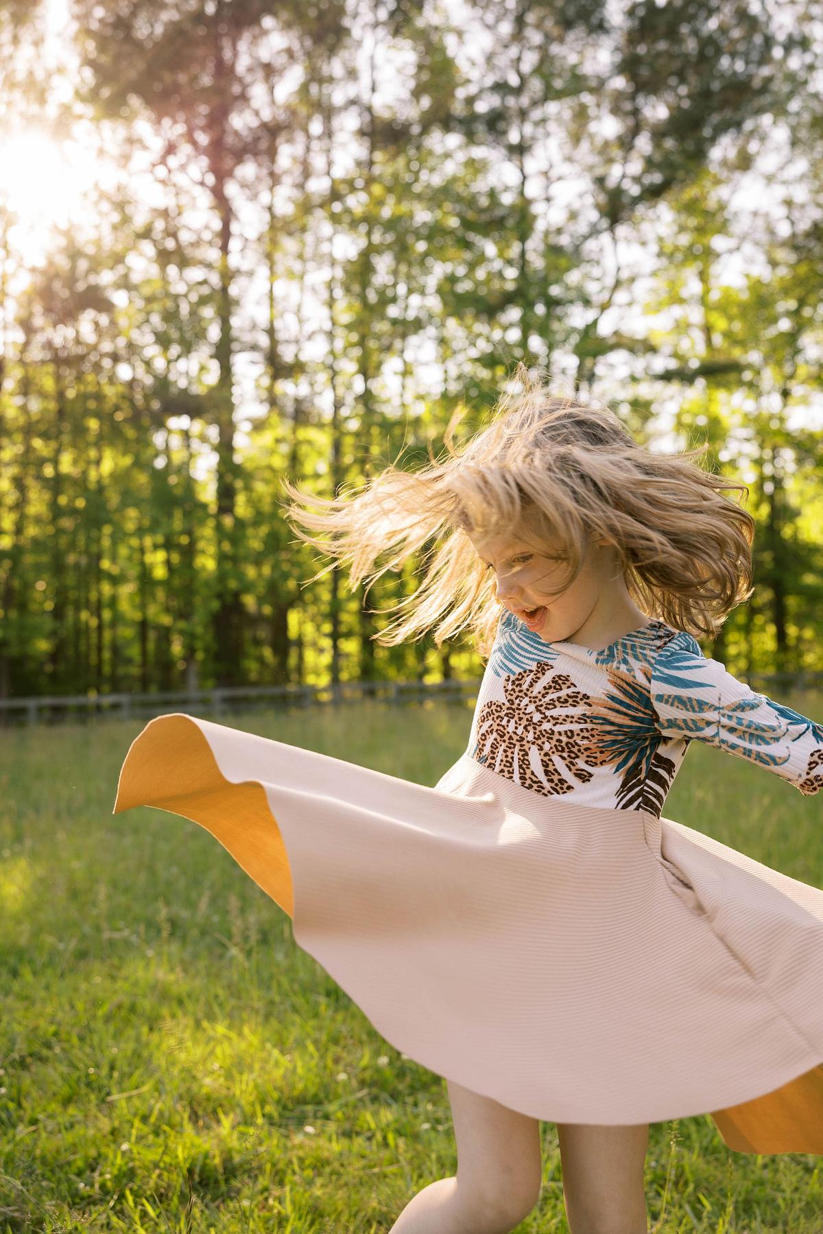 A young girl twirling her dress in a field at golden hour in Chapel Hill, NC