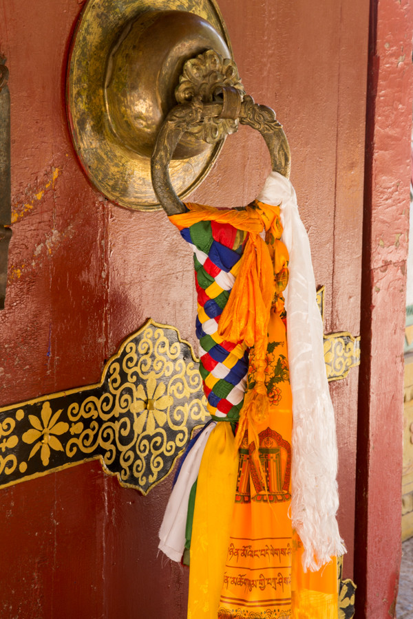 Large old brass door knocker with colorful cloth tied around it