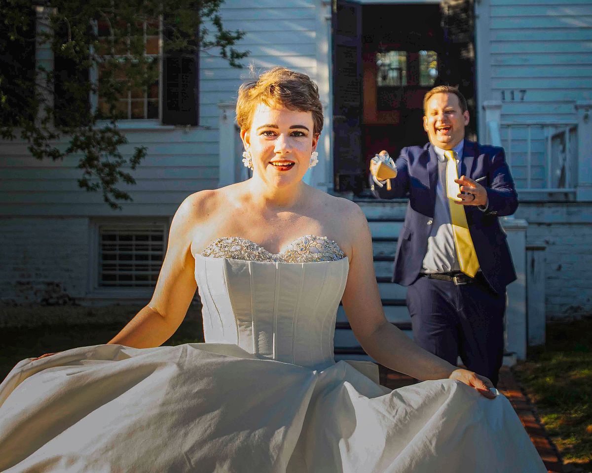 a laughing  bride is running away from her groom at poplar Hill mansion in Salisbury, md
