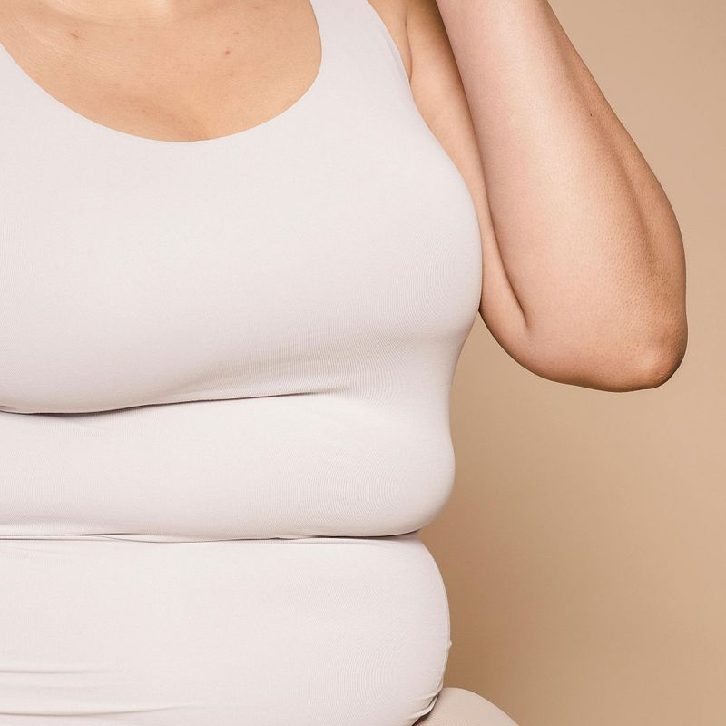 overweight woman in a tank top showing fat bulges and rolls