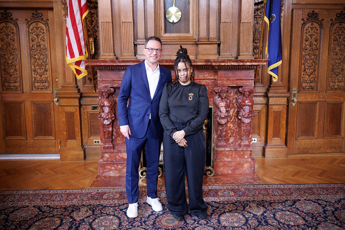 Governor Josh Shapiro speaks with Little Miss Black Pennsylvania during the CROWN Act signing in Harrisburg, capturing a candid moment of connection and representation in a historic leadership setting.