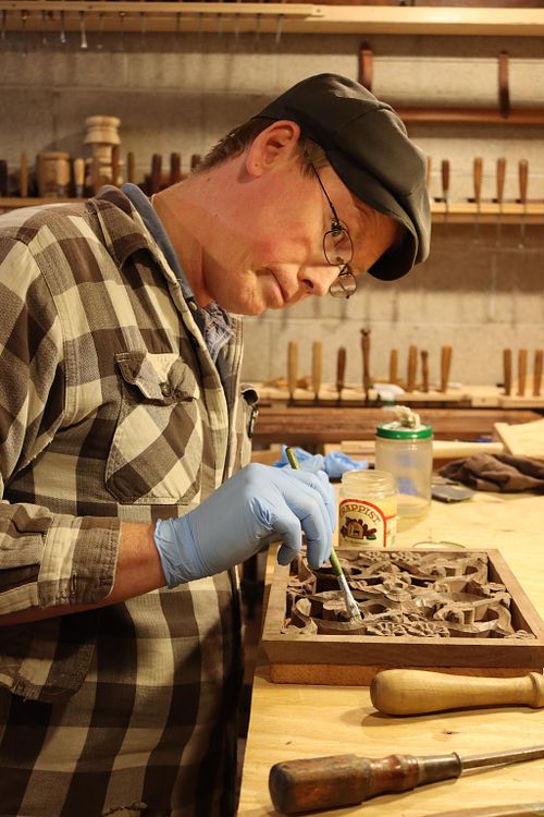 Wes Baker applying shellac finish by hand to one of the carving panels on the walnut baptismal font