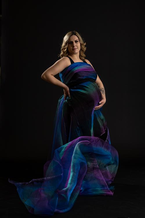 Creative portrait of expecting mother with rainbow fabric flowing around her.
