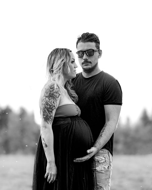 Moody black and white portrait of expecting couple.
