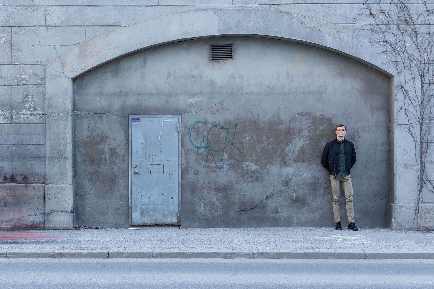 Founder portrait of male entrepreneur standing against concrete wall in Stockholm urban environment