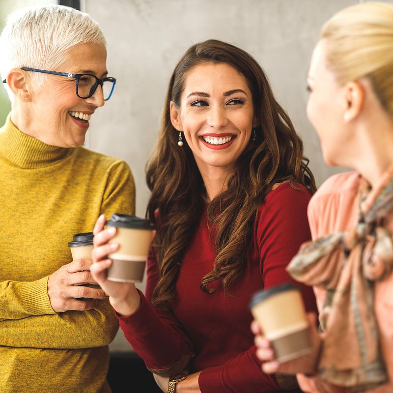 three women with coffee talking and smiling