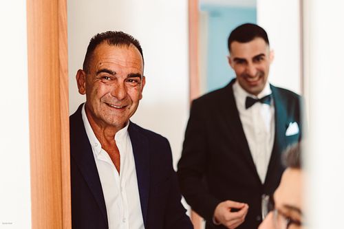 "invitati che sorridendo osservano lo sposo che si veste"