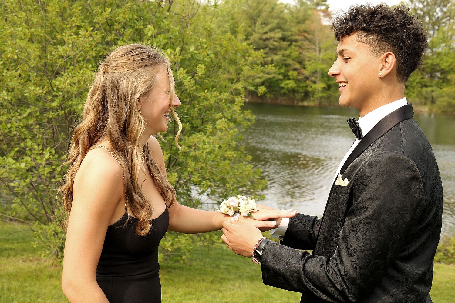 Boy puts corsage on girl's wrist during prom party