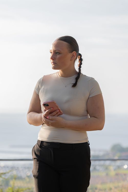 Kvinna i mjukt kvällsljus med mobil, redaktionellt miljöporträtt i Stockholm