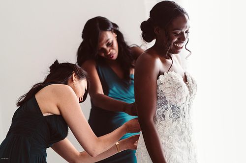 "sposa di spalle che viene vestita dalle damigelle"