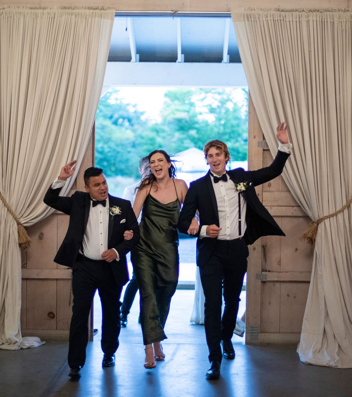 the bridal party is dancing during the introduction at kylan barn, the maid of honor is in the center and the groomsmen are holding her arms
