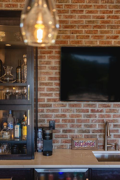 Close up of pendant light; brick; glass door cabinet, tv mounted on brick
