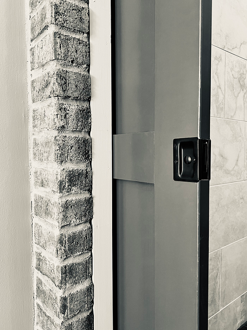 Full-coursed brick wall with solid wood pocket door built-in