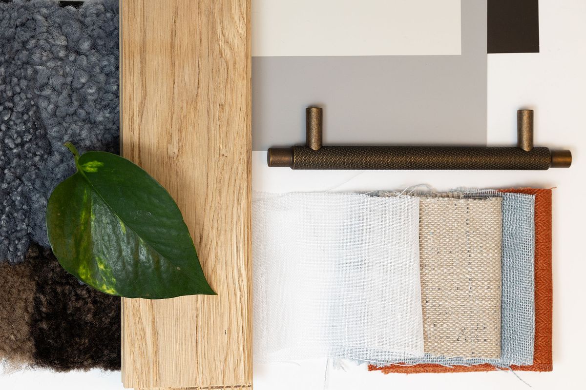 Flatlay med tygprover, tr&auml;prov, blad och beslag som moodboard f&ouml;r inredningsdesign och materialval.