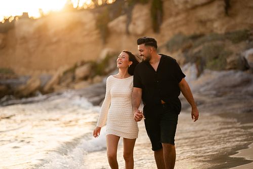 coppia innamorata ride passeggiando in spiaggia al tramonto
