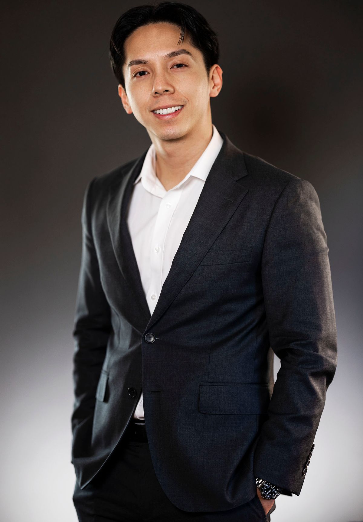 Corporate portrait of a business man in a black suit with a white shirt, A graduated white to black background.