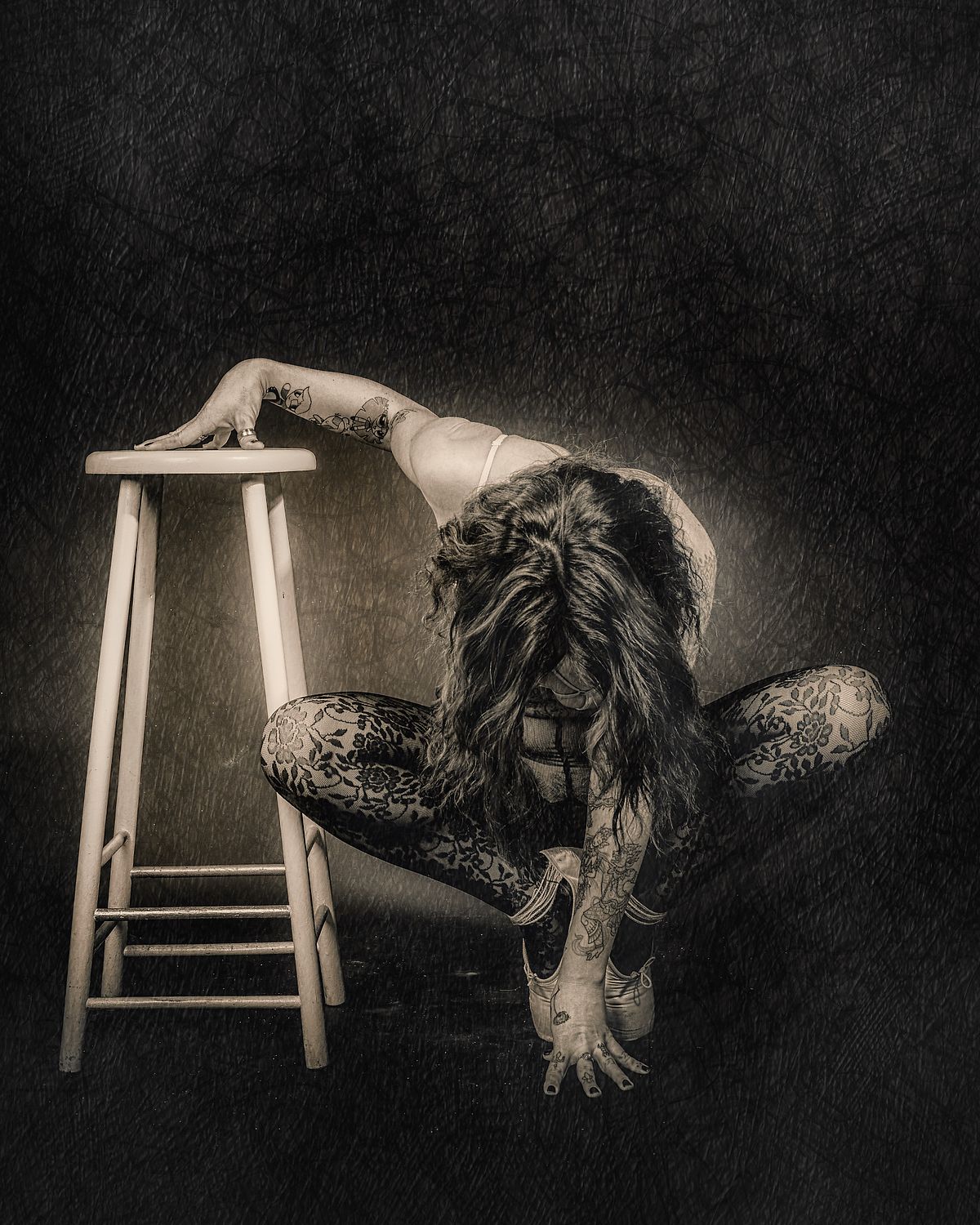 photo tarot Exhausted, femme accroupie sur tabouret, cheveux couvrant le visage, posture d'&eacute;puisement silencieux