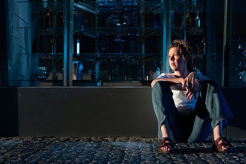 Editorial-style portrait of a woman sitting on cobblestone in blue-toned evening light, photographed in Stockholm by Mats Karlsson.