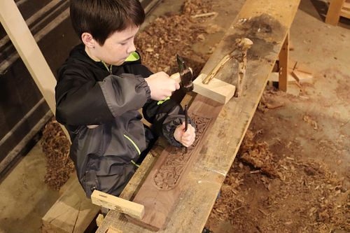 One of the Baker boys helps stipple the background of a carved panel