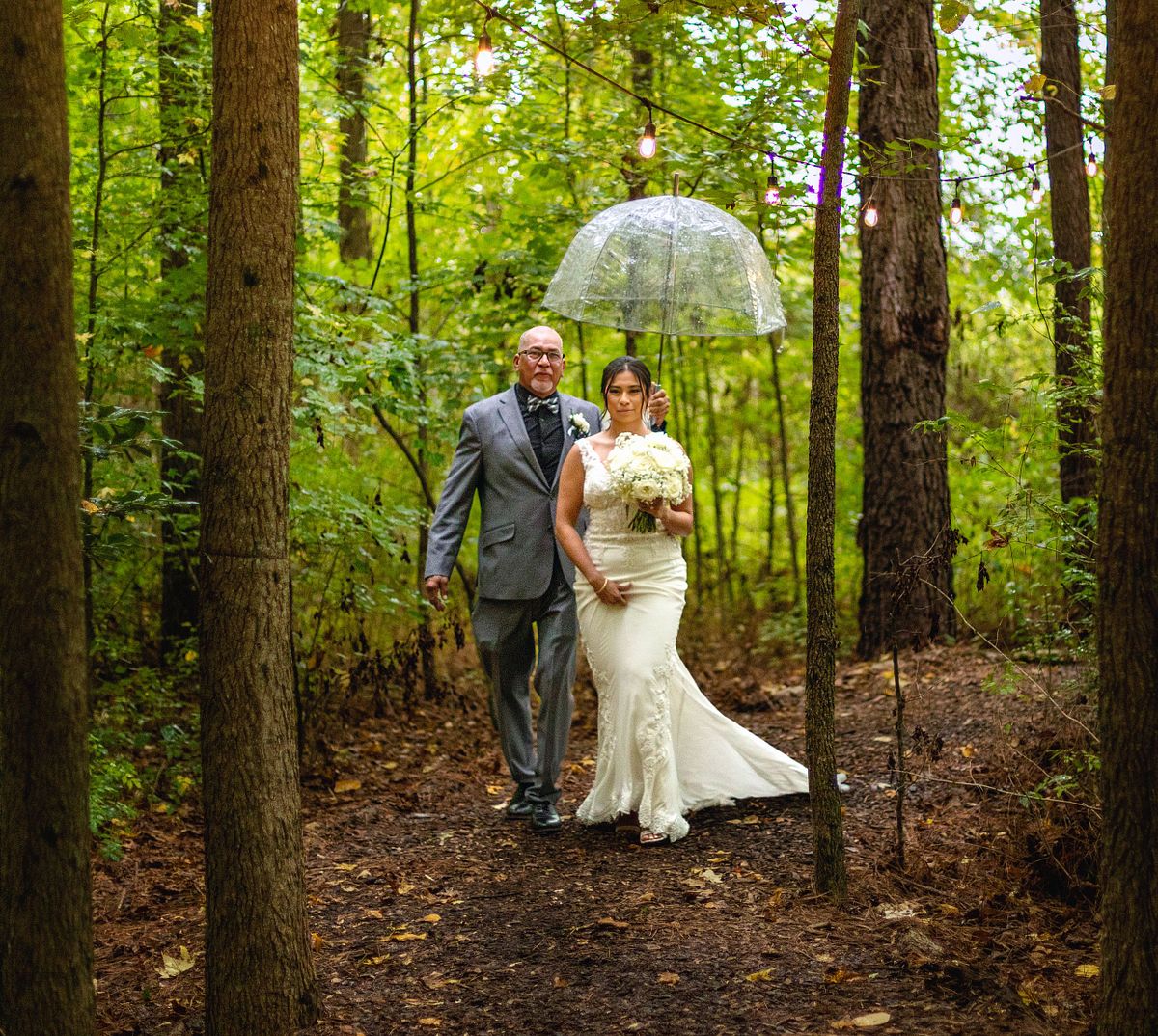 bride and dad walking down the path at kylan barn's woodland ceremony site