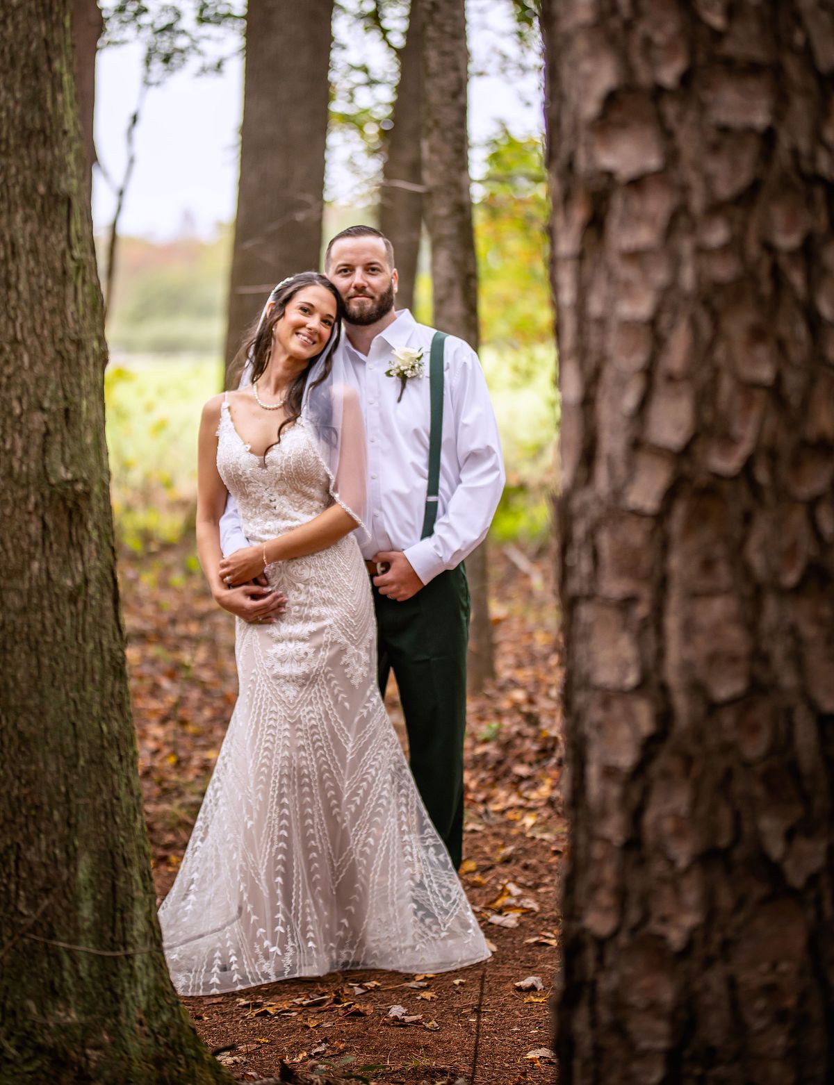 bride and groom posing between two trees after the ceremony at an eastern shore fall forest wedding