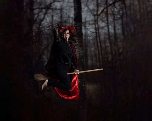A witch flies through the forest on her broomstick.