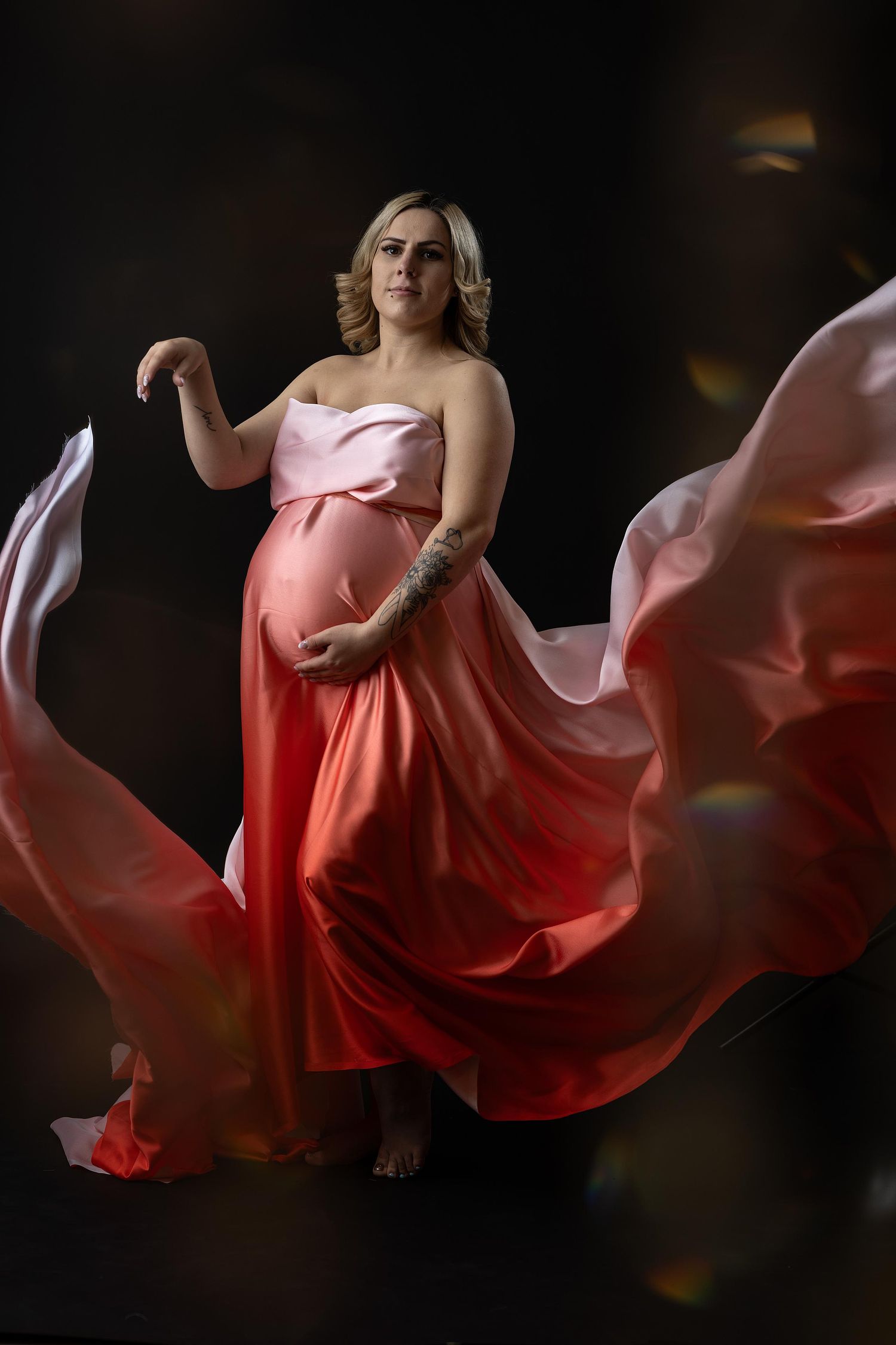 Creative portrait of a pregnant woman with her dress flowing around her.