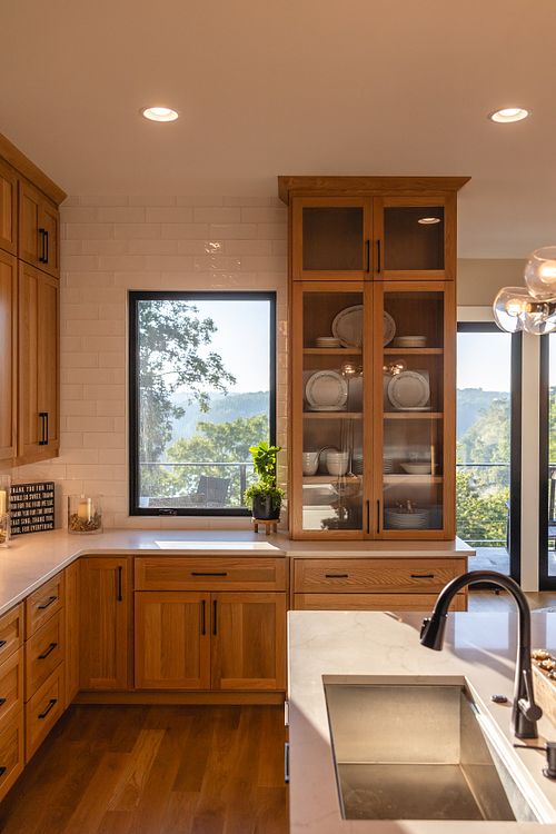 Large casement window for lake view from kitchen with full height glass door cabinet on the right side