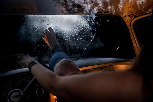 A woman trying to kick through a windshield as water rushes over the vehicle.