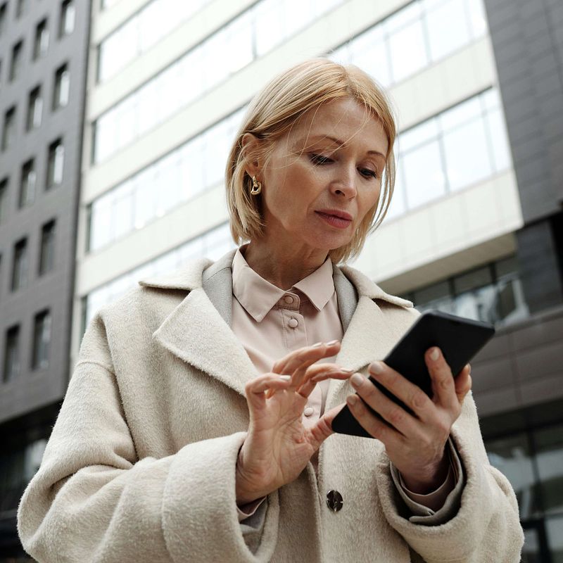 Menopausal woman looking contemplative at her phone looking for information