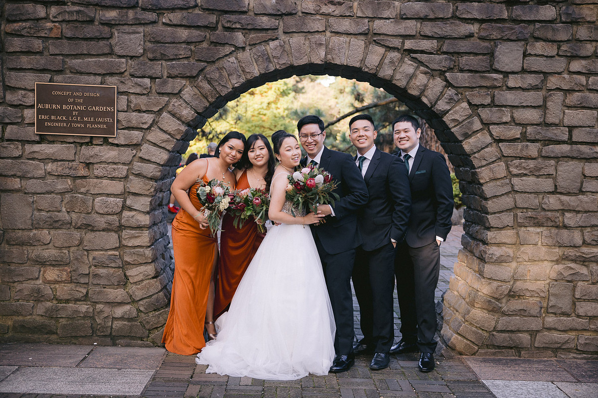 Wedding photography capturing the bridal party laughing and celebrating together at Japanese Garden Auburn Botanic Gardens.