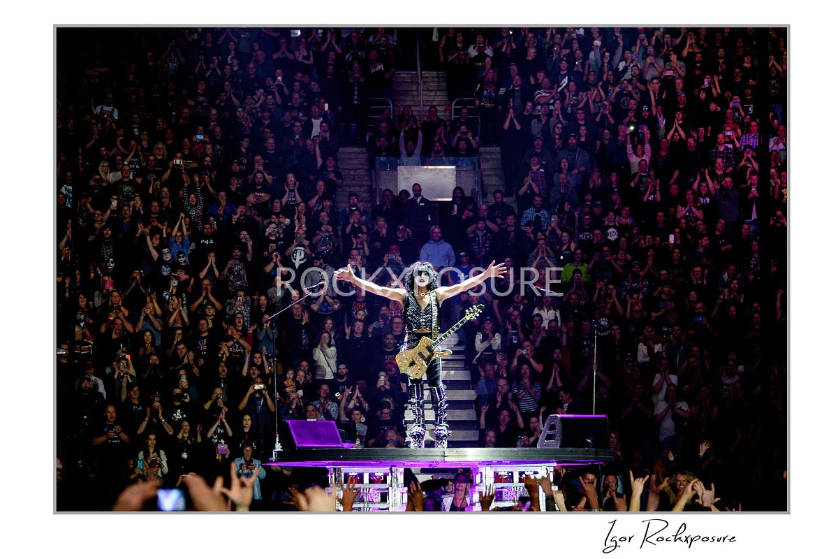 Paul Stanley standing on a small platform in the crowd with his hands raised