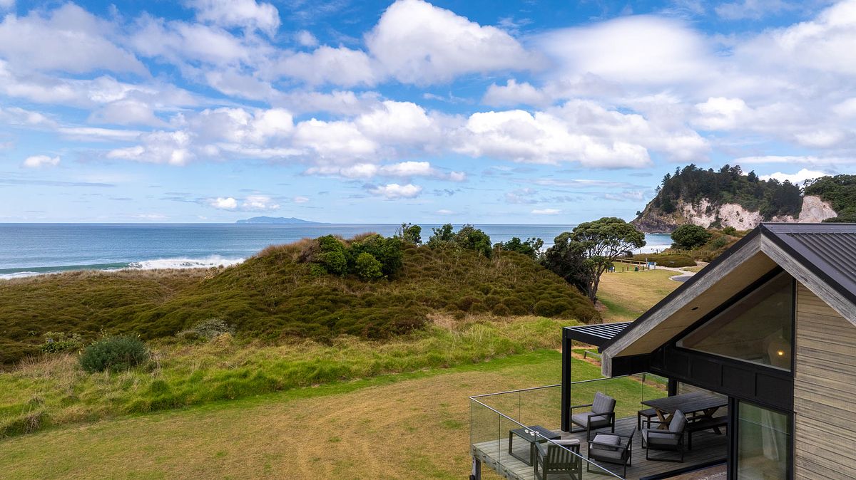 Cinematic drone photography of a luxury beachfront home in Whiritoa by Flax Cove Studio.